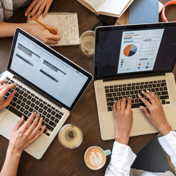 Tope view close up of women typing on laptop computers over cafe table with coffee cups
